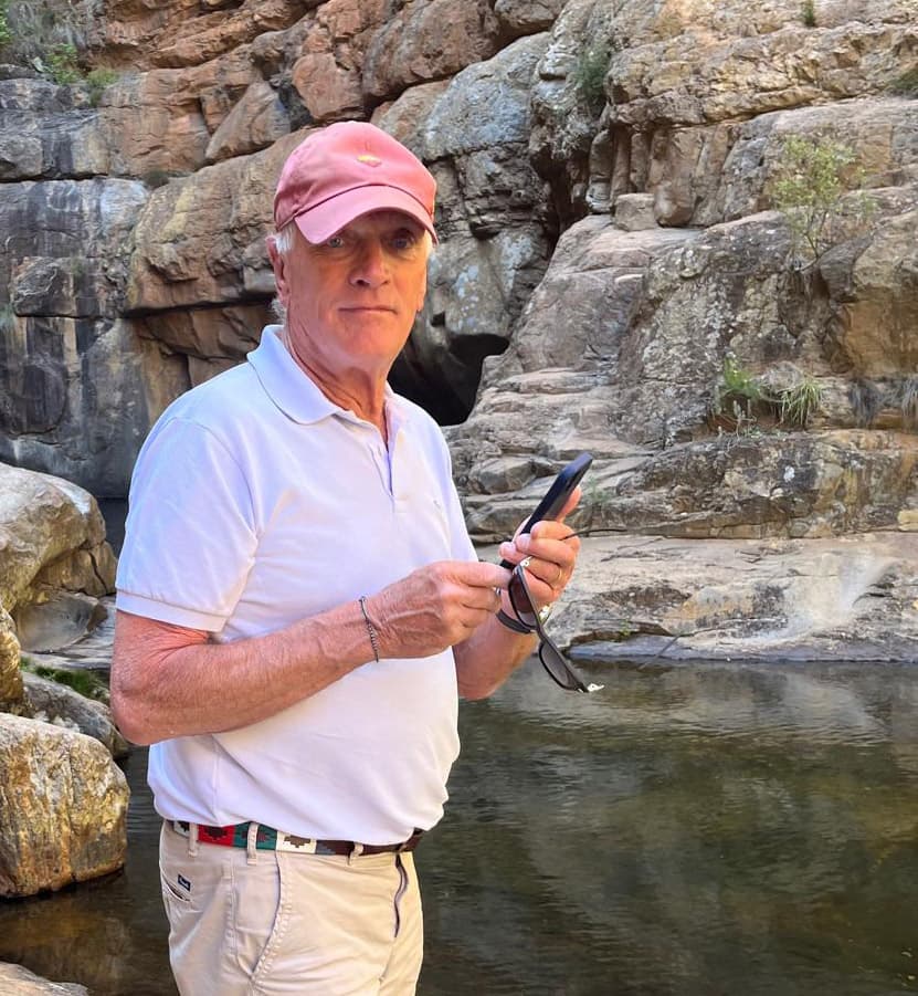 Stephen Parker by a rock pool, in a white polo shirt and red cap